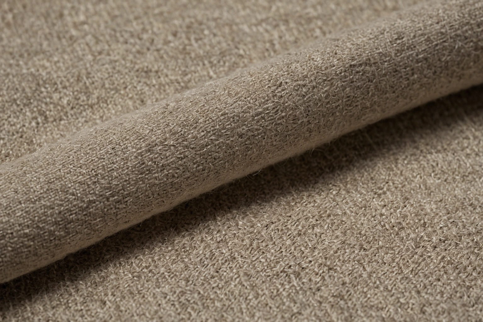 Folded lengths of upholstery fabric under low raking light, the surface relief of the weave thrown into shadow